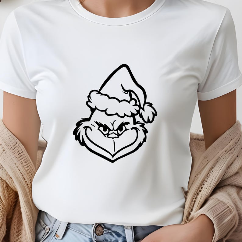 May include: White t-shirt with a black and white illustration of the Grinch wearing a Santa hat.