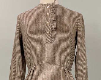 May include: A brown and white striped dress with a ruffled collar and cuffs. The dress has a button-up front and a fitted waist.