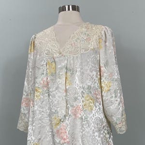 May include: A white satin robe with a floral print and lace trim. The robe has a V-neckline and long sleeves.