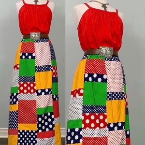 May include: A red sleeveless top with a patchwork skirt. The skirt is made of different colored fabrics with polka dots. The skirt has a brown belt with a silver buckle.