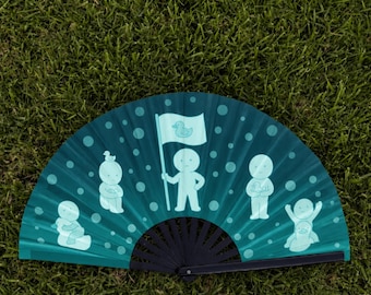 Puede incluir: Un abanico plegable con fondo azul verdoso oscuro que presenta un patrón de círculos azul verdoso claro y cinco figuras estilizadas. Una figura central sostiene una bandera con un icono de pato, mientras otras interactúan con patitos.
