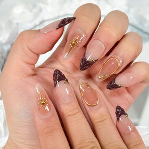 Uñas francesas marrones con punta prensada: set reutilizable de almendras largas con estrellas doradas 3D
