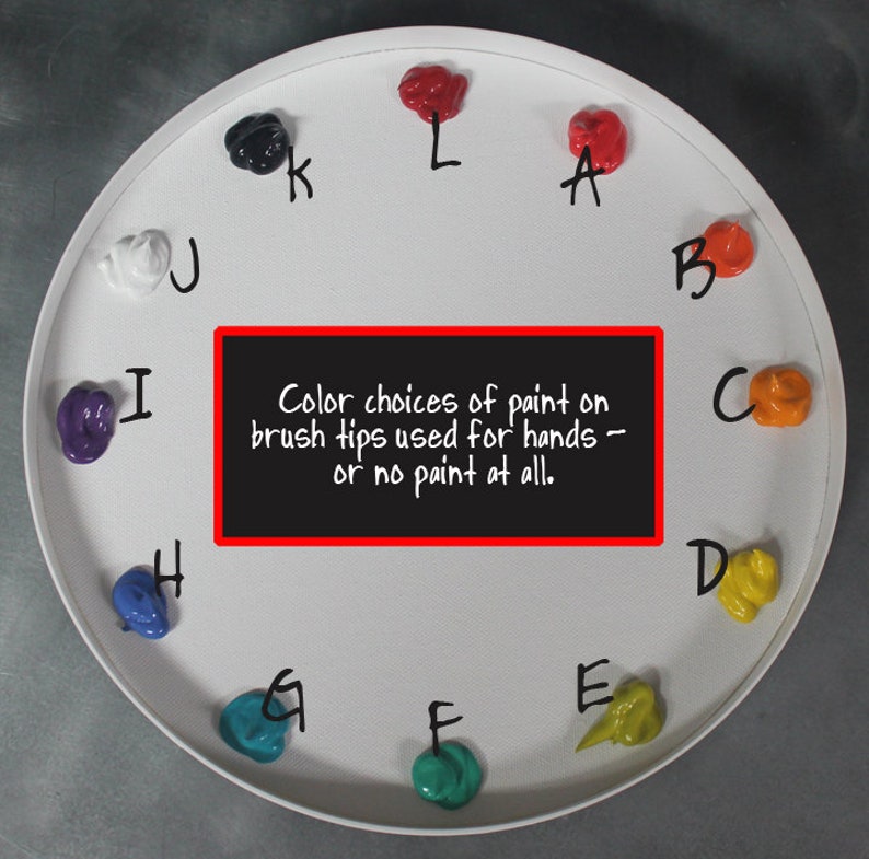 May include: A circular white palette featuring twelve distinct dollops of colored paint arranged in a clock-like pattern, each labeled with a letter from A to L. A central black rectangular sign displays the text: Color choices of paint on brush tips used for hands &ndash; or no paint at all.