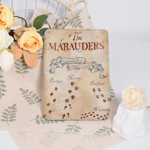 Könnte beinhalten: Rechteckiges Schild mit dem Text "The Marauders" im Vintage-Stil. Das Schild enthält den Satz "I solemnly swear I am up to no good" und Pfotenabdrücke. Die Namen "Prongs", "Moony", "Padfoot" und "Wormtail" sind ebenfalls vorhanden.