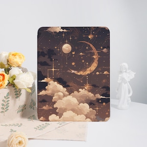 May include: A tablet case featuring a celestial design with a crescent moon, stars, and clouds in shades of brown, beige, and gold. The case has a rectangular shape and a smooth surface. The overall theme is a dreamy, night sky.