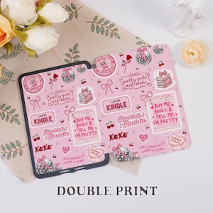 May include: Pink Kindle case with a repeating pattern of bows, books, cherries, and text. The case features phrases like "I love my Kindle", "Bookish Baddie", and "Pretty girls read books". The case is designed for a Kindle.