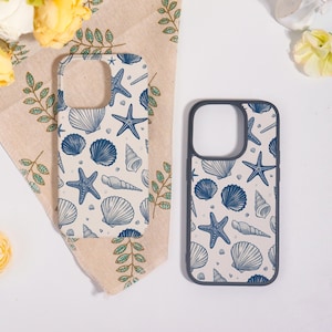 May include: Two phone cases featuring a cream background adorned with blue seashells and starfish. One case rests on a beige cloth with green leaf accents and yellow flowers. The other has a dark grey border.