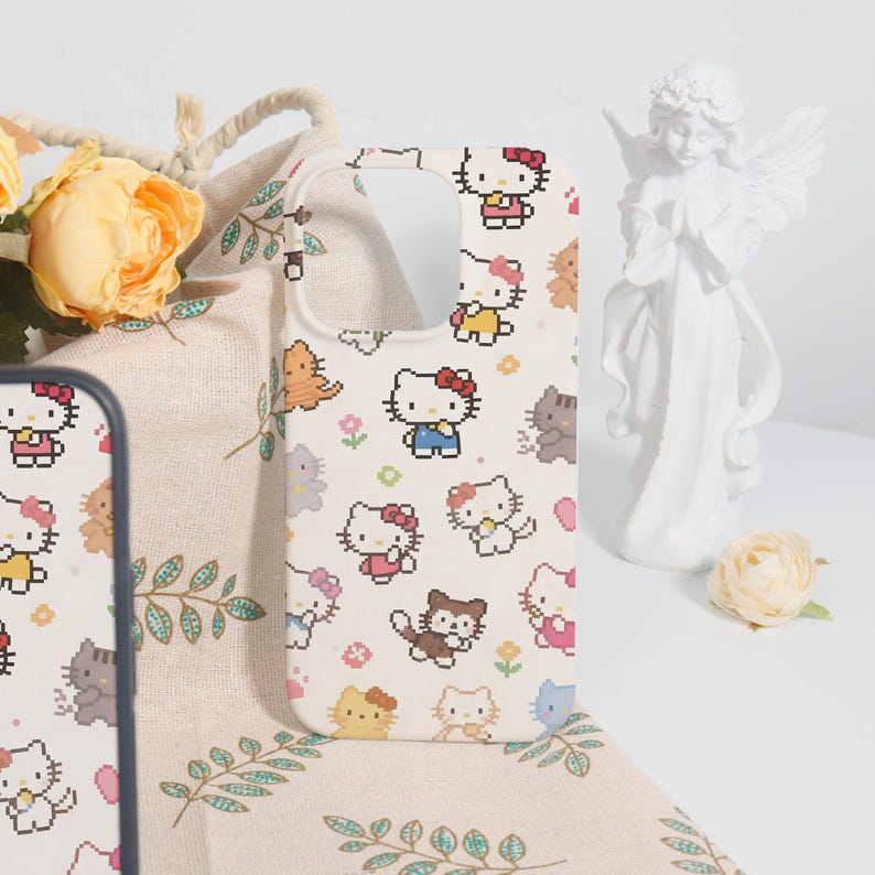 May include: White phone case featuring a repeating pattern of pixelated Hello Kitty characters and other cute animals. The case has a cutout for the camera and buttons. The background is a beige fabric with floral and leaf patterns.