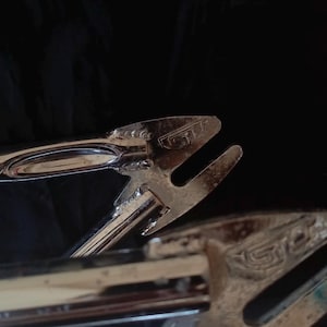 May include: Close-up of a chrome bicycle frame with the text "GT" stamped on the frame.