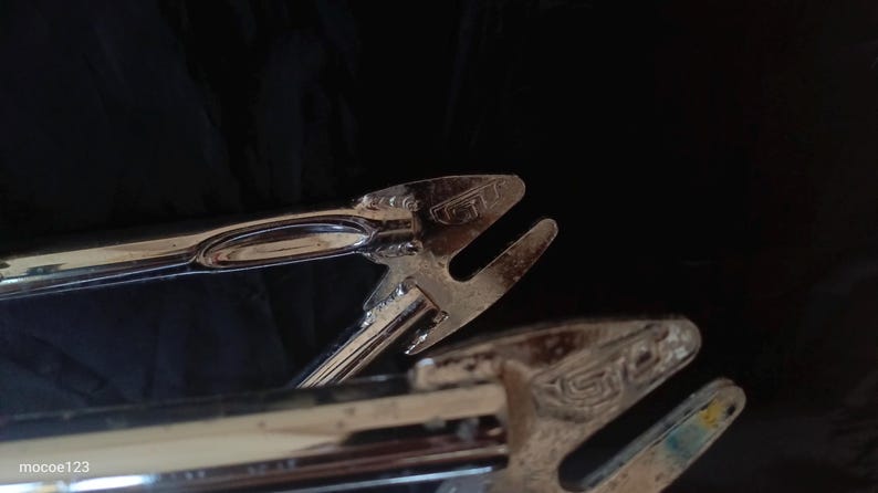 May include: Close-up of a chrome bicycle frame with the text "GT" stamped on the frame.