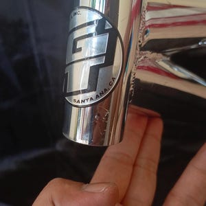 May include: Close-up of a chrome bicycle frame with a GT logo and the text "Santa Ana, CA" on a black background.