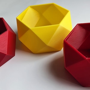 May include: Three geometric planters, one yellow and two red, made of 3D printed plastic. The planters have a unique, faceted design.