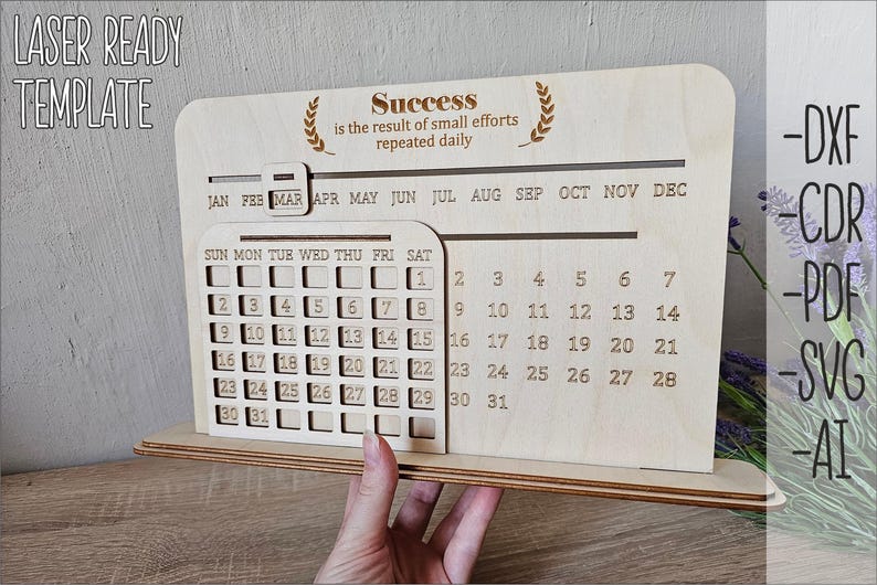 K&ouml;nnte beinhalten: Ein h&ouml;lzerner Desktop-Kalender mit einem monatlichen Kalenderraster und einem Zitat, das lautet "Erfolg ist das Ergebnis kleiner Anstrengungen, die t&auml;glich wiederholt werden". Der Kalender ist lasergeschnitten und bereit zum Zusammenbauen.