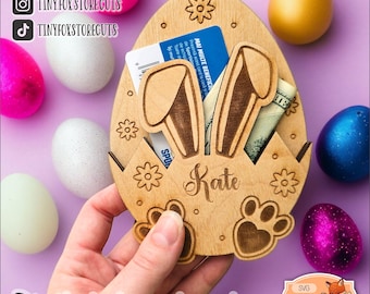 May include: A wooden Easter egg-shaped box with bunny ears, a slot for cash, and a personalized name "Kate". The box is decorated with flowers and paw prints.