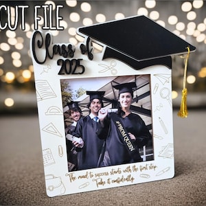 May include: A laser-cut photo frame with a graduation theme. The frame features the text "Class of 2025" and a graduation cap. The frame holds a photo of three graduates. The text "The road to success starts with the first step. Take it confidently" is also included.
