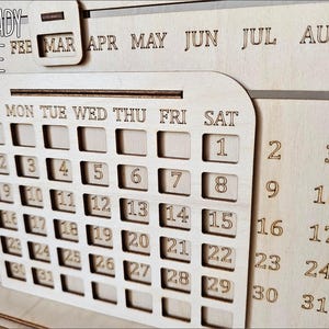 K&ouml;nnte beinhalten: Lasergeschnittenes Holzkalender-Template mit Wochentagen und Zahlen von 1 bis 31. Das Template ist bereit zum Zusammenbauen und als Tischkalender zu verwenden. Das Bild zeigt das Template in einer hellen Holzfarbe.