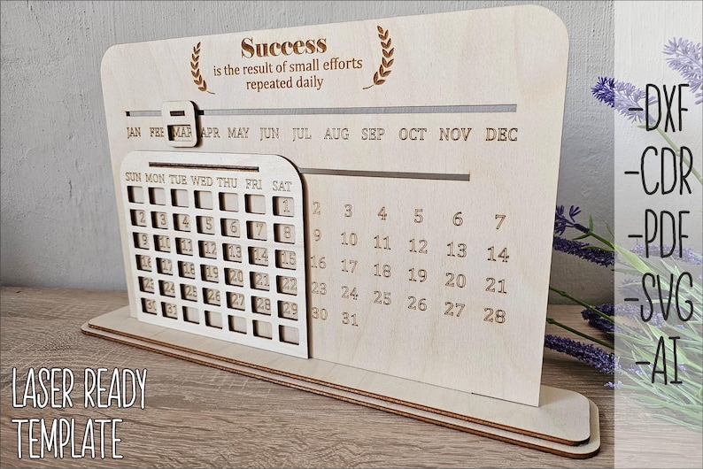 K&ouml;nnte beinhalten: Ein lasergeschnittener Holz-Desktop-Kalender mit einem monatlichen Kalenderrraster und einem Zitat, das lautet "Erfolg ist das Ergebnis kleiner Anstrengungen, die t&auml;glich wiederholt werden". Der Kalender ist so konzipiert, dass er zusammengebaut und personalisiert werden kann.