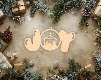 May include: Wooden Christmas ornament spelling "JOY", with a nativity scene in the letter "O". The ornament is surrounded by pine branches, wrapped gifts, pine cones, and other festive decorations. The background is a neutral, textured surface.