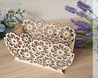 May include: Laser cut wooden box with a floral design. The box is made of light brown wood and has a delicate pattern of flowers and leaves. The box is perfect for storing small items or as a decorative piece.
