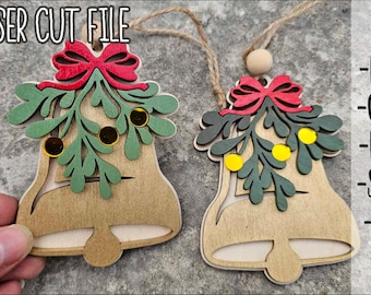 May include: Two wooden bell ornaments featuring laser cut mistletoe sprigs with green leaves, yellow berries, and a red bow at the top. The text LASER CUT FILE is at the top left, and the file formats DXF, CDR, PDF, SVG, and AI are listed on the right.