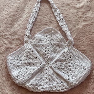 May include: White crocheted tote bag with a square pattern and two straps.
