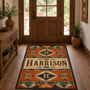 May include: A rectangular area rug featuring a geometric pattern in shades of orange, teal, and brown. The rug displays the name HARRISON in large dark letters across the center, flanked by two diamond motifs containing the letter H.
