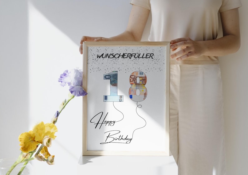K&ouml;nnte beinhalten: Ein wei&szlig;er gerahmter Druck mit dem Text "Wunscherrfuller" und den Zahlen "18" aus Euro-Scheinen. Die Zahlen sind wie Ballons mit Schn&uuml;ren geformt. Der Text "Happy Birthday" befindet sich unter den Zahlen.