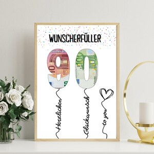 May include: A framed print with the number 90 formed from Euro banknotes. The text "Wunscherf&uuml;ller" is at the top, with "Herzlichen" and "Gl&uuml;ckwunsch to you" below. A heart is drawn on the right side.