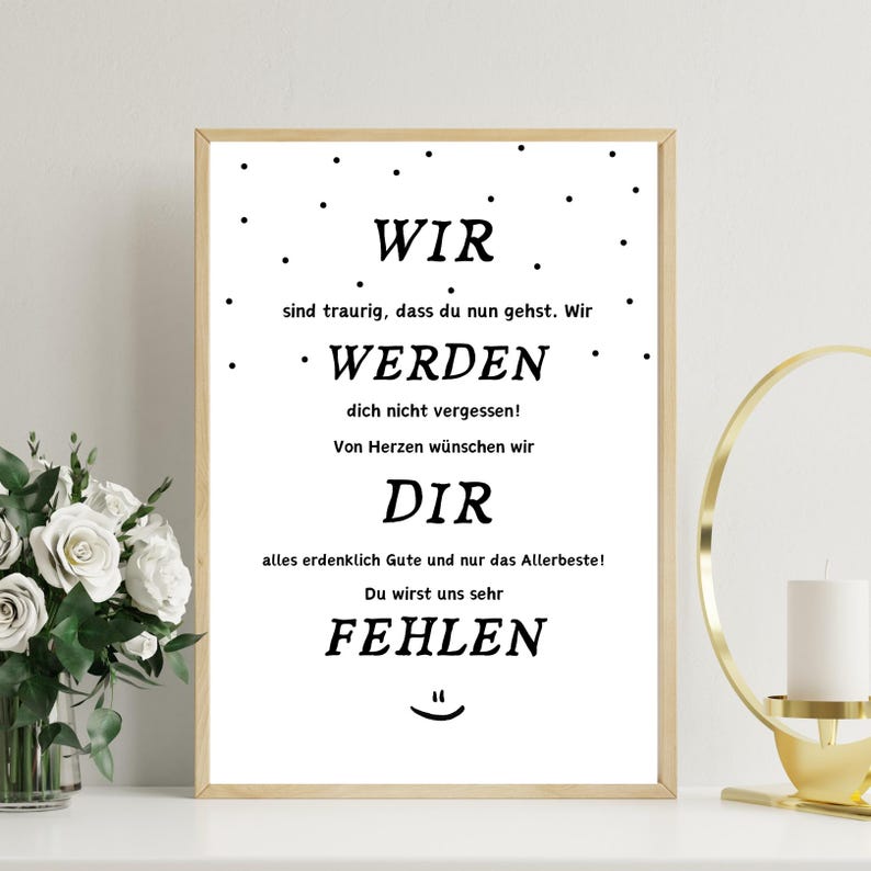 May include: A framed print with a light wood frame. The white background features black text in a simple font. The text reads "WIR WERDEN DIR FEHLEN" in German, with additional phrases. Black dots are scattered around the text.