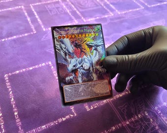 May include: A blue-eyed white dragon card with a holographic finish. The card features a powerful dragon with three heads and a blue background. The card text reads "Dragon Master Knight" and "ATK/3500 DEF/2500".