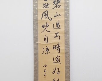 Puede incluir: Un rollo beige con caligrafía negra sobre un fondo beige. El rollo tiene un borde rojo y dorado. El texto en el rollo dice: "風雲際会", que se traduce como "Encuentro del viento y las nubes".