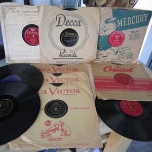May include: A collection of vintage vinyl records from various labels including Decca, Columbia, RCA Victor, Mercury, and Capitol. The record sleeves are in various colors and feature the label's logos and text.