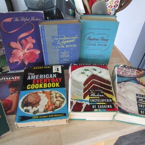 May include: A collection of vintage cookbooks with colorful covers. The titles include "The Perfect Hostess", "The Prudence Penny Regional Cook Book", "Prudence Penny Cook Book", "The American Everyday Cookbook", "Meta Given's Modern Encyclopedia of Cooking".