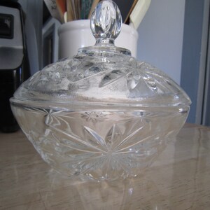 May include: A clear glass candy dish with a starburst pattern and a knobbed lid.