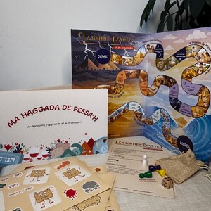 Peut inclure: Un jeu de société avec les titres "LA SORTIE EGYPTE" et "MA HAGGADA DE PESSA'H". Le jeu comprend un plateau de jeu, des cartes, des dés, des pions et un petit sac en toile de jute. Le plateau de jeu présente des illustrations et du texte.