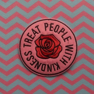 May include: Pink fabric patch with a red embroidered rose and the text "Treat People With Kindness" in black.