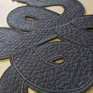 Op de afbeelding: Close-up van een donkergrijze geborduurde slangenpatch met een getextureerd oppervlak. De slang is opgerold en gedetailleerd, met een zwarte rand. De patch is waarschijnlijk voor kleding of accessoires.