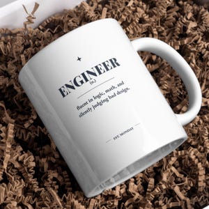 Puede incluir: Una taza de cerámica blanca con texto en negro que dice ENGINEER (n.) fluent in logic, math, and silently judging bad design. EST. MONDAY. La taza tiene un asa curva y está colocada en ángulo, mostrando claramente la definición impresa.