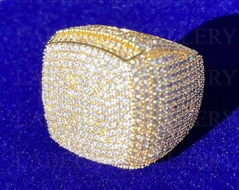 May include: A gold ring with a square face covered in small, clear stones.
