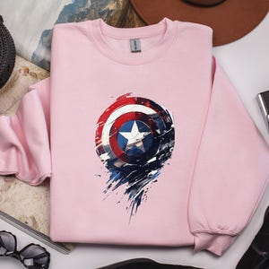 a pink sweatshirt with a captain america design on it
