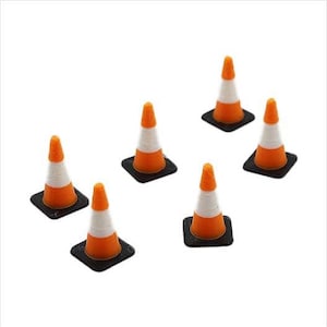 Op de afbeelding: Zes miniatuur oranje en witte verkeerskegels met zwarte bases. De kegels zijn in een halve cirkel op een witte achtergrond gerangschikt.