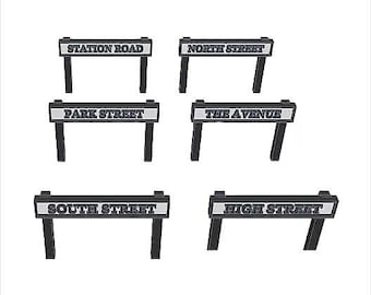 May include: Six black and white street signs with white lettering on a white background. The signs read "Station Road", "North Street", "Park Street", "The Avenue", "South Street", and "High Street".