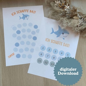May include: Two white paper prints with a shark illustration and the text "ICH SCHAFFE DAS!". One print has blue circles, the other has numbered circles. The text "digitaler Download" is on a blue starburst.