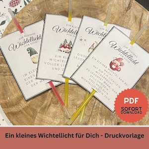 May include: Four white cards with the text "Ein kleines Wichtellicht für Dich" and illustrations, each with a different design. The cards are accompanied by yellow and red glow sticks. A red PDF button is in the bottom right.