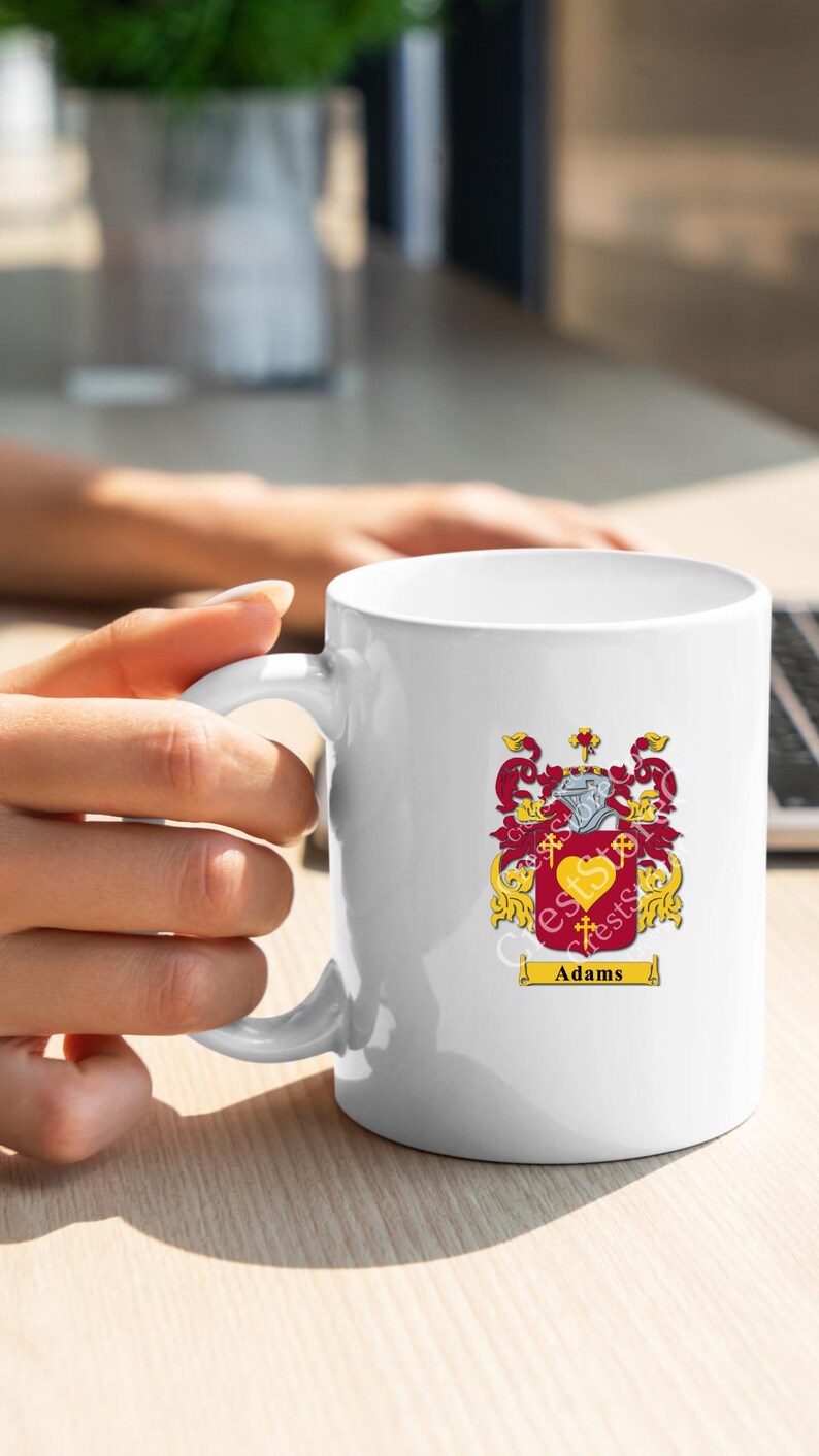 May include: White ceramic mug with a gold and red coat of arms design and the name "Adams" printed below.