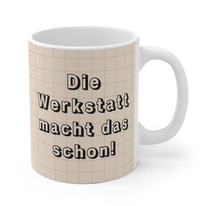 May include: A white ceramic mug featuring a beige grid pattern background and the black text Die Werkstatt macht das schon! printed on the front. The mug has a smooth finish, a rounded handle, and a clean white interior, providing a functional vessel.