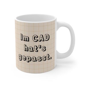 May include: White ceramic mug with a beige graph paper design. The mug features the text "Im CAD hat's gepasst" in black, bold lettering. The mug has a white handle and is suitable for hot or cold beverages.