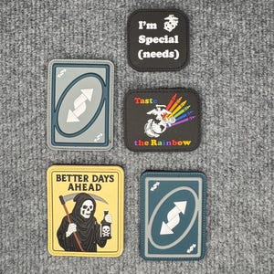 May include: Five patches with various designs. One patch says "I'm Special (needs)". Another features a rainbow and the text "Taste the Rainbow". Two patches are designed like Uno cards. The last patch has a grim reaper and the text "Better Days Ahead".