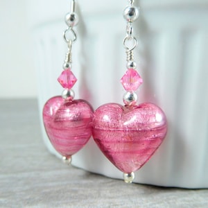 May include: Pink heart shaped glass earrings with silver hooks and pink crystal accents.