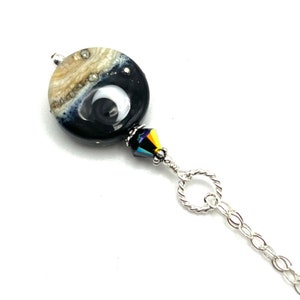 May include: A silver chain necklace with a black and white glass bead and a crystal accent.
